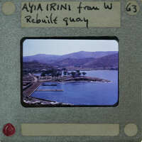 A vintage photograph of a harbor with mountains in the background, enclosed within an old film strip holder.