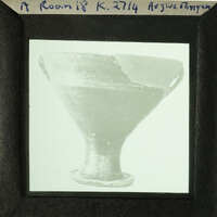 A black and white photograph of an ancient Greek drinking cup with visible cracks.