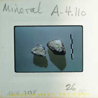 Two small rocks on a white background with measurement markings.