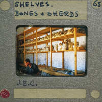A man working at a pottery workshop with shelves full of clay pots.