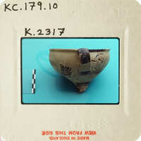 Ancient pottery artifact on display with visible markings and damage.