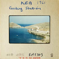 A photograph of an island harbor with buildings and boats, taken from a high vantage point.