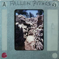 A photograph of a fallen pithos, which is an ancient Greek storage jar, with handwritten notes on the film strip.