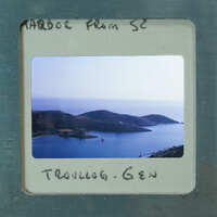 A photograph of a scenic bay with islands and boats, enclosed within an old film strip frame.