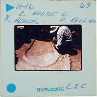 Man working on a large stone bowl or basin, possibly at an archaeological site.