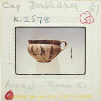 A photograph of a ceramic cup with markings, displayed on a card labeled "CUP DOUBLE AXES" with handwritten notes and stamps.