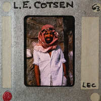 A man wearing a headscarf and standing in front of a stone wall.