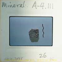 A small, dark rock on a light surface with a label and number.