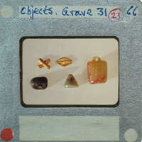 A collection of small objects, including beads and stones, displayed on a white surface with labels indicating they are from "Tomb 31".