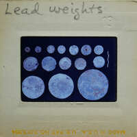Image of circular lead weights on a card with handwritten notes.