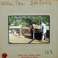 Two people repairing terracotta statues outdoors.