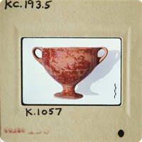 Ancient ceramic cup with handle and base on display.