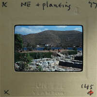A vintage photograph of a scenic landscape with mountains, water, and vegetation on a film strip.