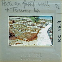 A vintage photograph of a stone wall and tower with handwritten notes on the back.