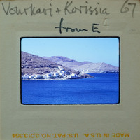 A coastal village with blue water and mountains.