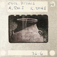 A vintage photo of a large, cracked clay pot with a handle.