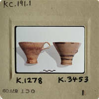Two clay cups with handles on a white surface.