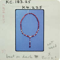 Red bead necklace with a tassel on a blue background.