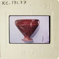 Ancient red clay pottery artifact with visible cracks and damage, photographed on a white background.