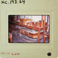 A photograph of a room with wooden shelves and debris on the floor, enclosed within an old film negative strip.