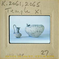 Two ancient Greek vases on display, one with visible cracks and chips.