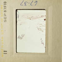 A blurry photograph of an outdoor scene, possibly taken with a telephoto lens, showing a path leading into a rocky landscape.