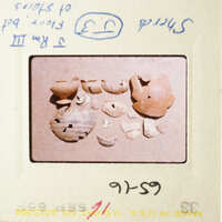 The image shows a collection of broken pottery pieces on a table.