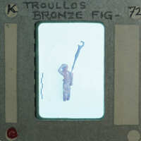 A small figurine of a person with a staff, encased in a plastic holder labeled "Bronze Figurine".