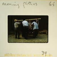 Four men working together to move a large object on a wooden platform.