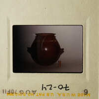 A photograph of an old slide showing a brown vase on a white surface.
