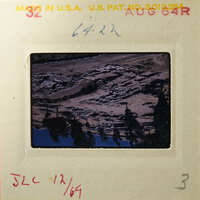 Aerial view of rugged terrain with trees, captured on an old photographic slide.