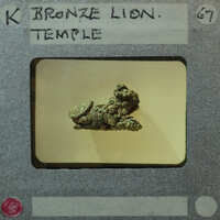 Small bronze statue of lion from the side in poor condition.