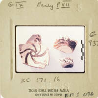 Photograph of ancient pottery shards with intricate designs on a white surface.