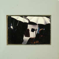 Photographer with umbrellas and lights, taking a portrait of a person.