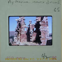 Old, crumbling stone ruins with a clear sky and mountains in the background.
