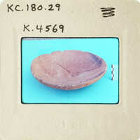 Old ceramic bowl with cracks and chips on blue surface.