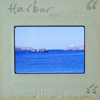 A vintage photo of a harbor with boats and calm waters, framed by an old film strip.