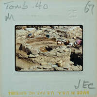 Ancient ruins with stone walls and a dirt floor, partially excavated and surrounded by debris.