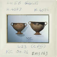 Two ancient Greek vases on display with labels and identification numbers.