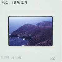 Aerial photograph of a coastal landscape with mountains and ocean.