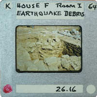 The image is a photograph of an earthquake-damaged area with debris and rubble, captured on a faux filmstrip label.