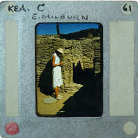 The image shows a person standing near an old stone structure, possibly ruins, with a vintage film strip border around the photo.