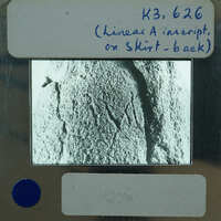 A black and white photograph of a stone surface with markings, displayed on an old-fashioned film strip.