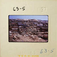 Old stone wall with weathered stones and dirt ground.