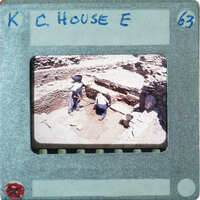 A photograph of two people working at an archaeological site with walls and a doorway.