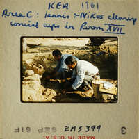 Two men working on cleaning and restoring ancient artifacts, possibly pottery, at an archaeological site.