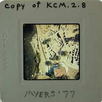 The image is a photograph of an archaeological site with ruins, surrounded by water.