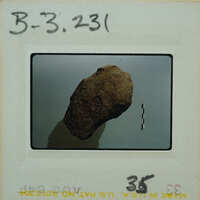 Picture of a rock on a white surface with a label and barcode.