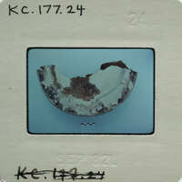 A damaged, broken ceramic object with a visible crack and fragments on a blue surface.