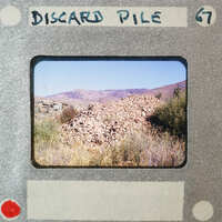 A photograph of a pile of rocks with mountains in the background, placed on a film strip labeled "Discard Pile".